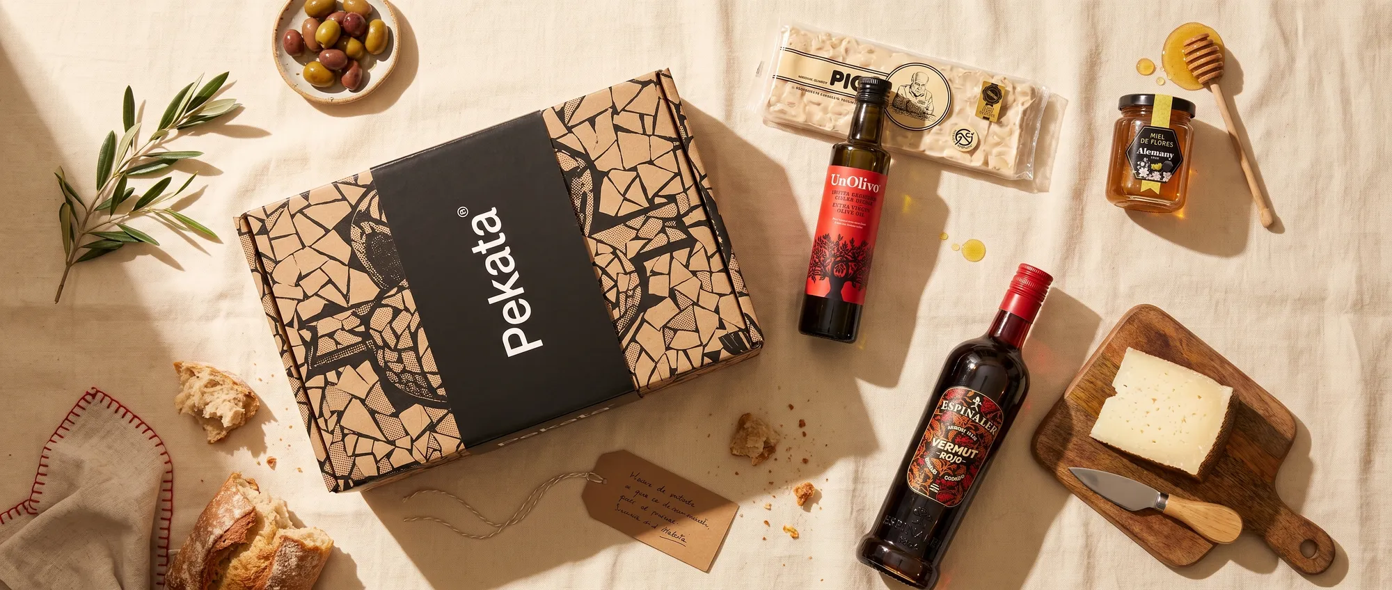 Caja de lote de Navidad Pekata con turrón artesano, miel, aceite y vermut sobre una mesa