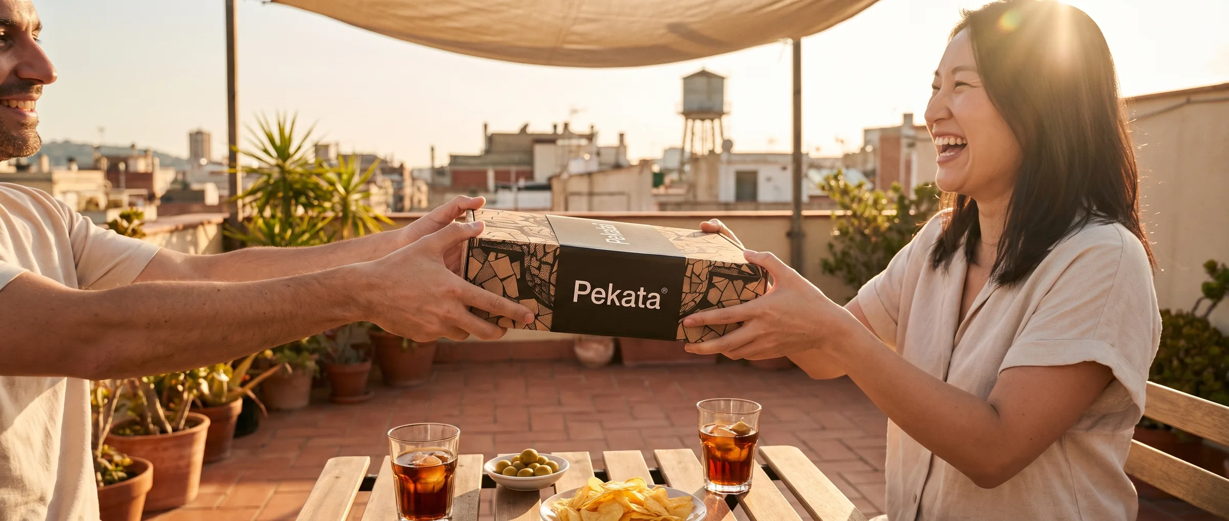 Dos amigos pasándose una caja Pekata en una azotea de Barcelona